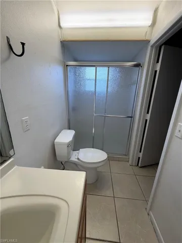 Bathroom with vanity, a stall shower, light tile patterned floors, and a textured wall