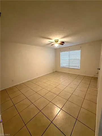 Empty room featuring light tile patterned flooring, ceiling fan, and a textured ceiling
