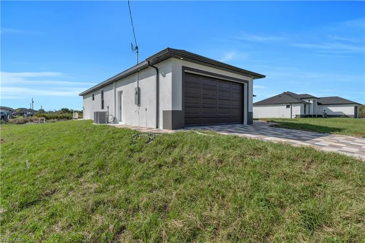 View of home's exterior with driveway, a yard, and stucco siding
