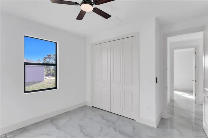 Unfurnished bedroom featuring a ceiling fan, a closet, and light marble finish flooring