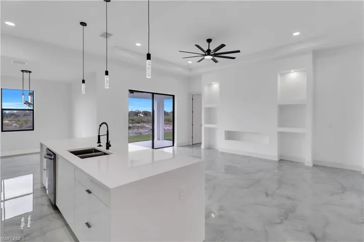 Kitchen with light marble finish flooring, modern cabinets, pendant lighting, built in features, and white cabinets