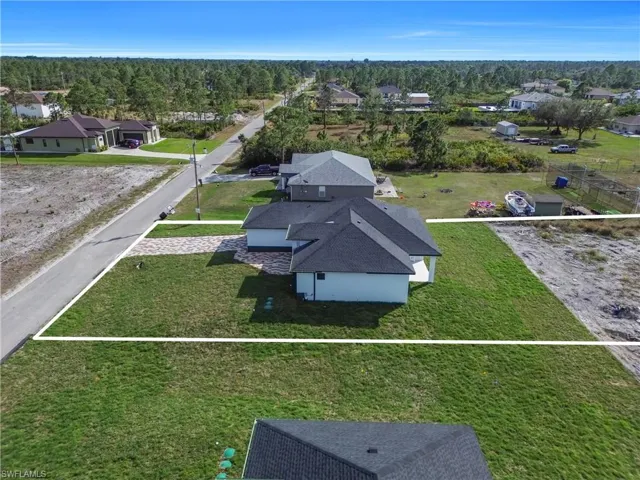 Aerial perspective of suburban area featuring property boundaries highlighted and a forest