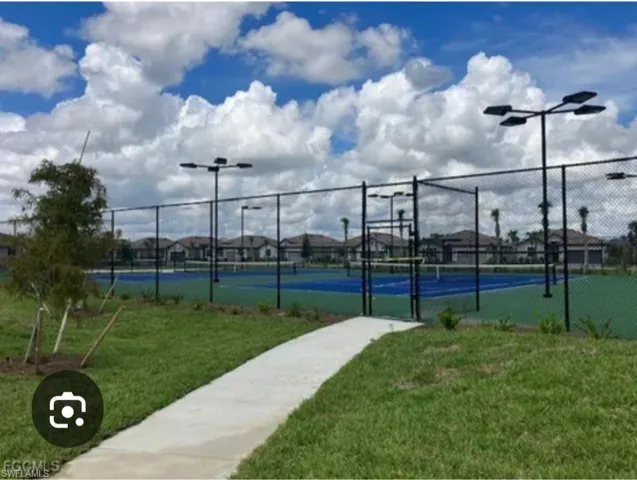 View of tennis court with a gate and a residential view
