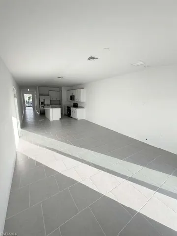 Unfurnished living room with light tile patterned floors and baseboards