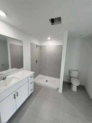 Full bath featuring a shower stall, vanity, and light tile patterned flooring