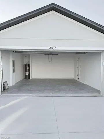 Garage with concrete driveway, electric water heater, and electric panel