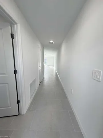 Hallway featuring baseboards and light tile patterned flooring