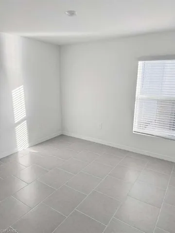Spare room featuring light tile patterned floors and baseboards