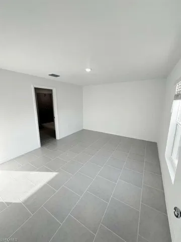Empty room with light tile patterned floors and recessed lighting