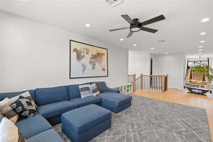Living room featuring wood finished floors, a ceiling fan, visible vents, and recessed lighting