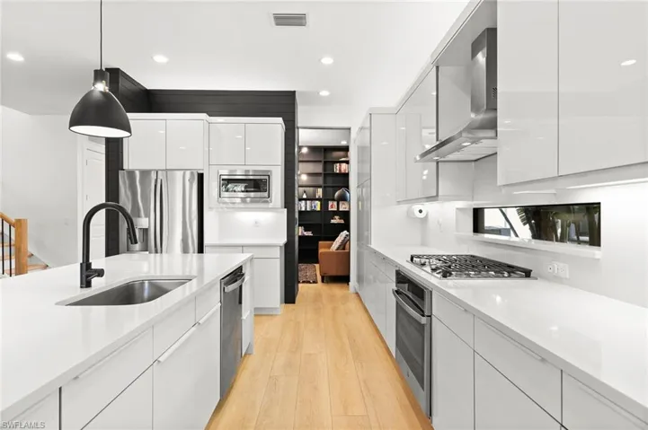 Kitchen featuring appliances with stainless steel finishes, a sink, modern cabinets, and wall chimney exhaust hood