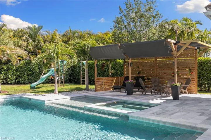 Outdoor pool featuring a patio area, an in ground hot tub, and a playground