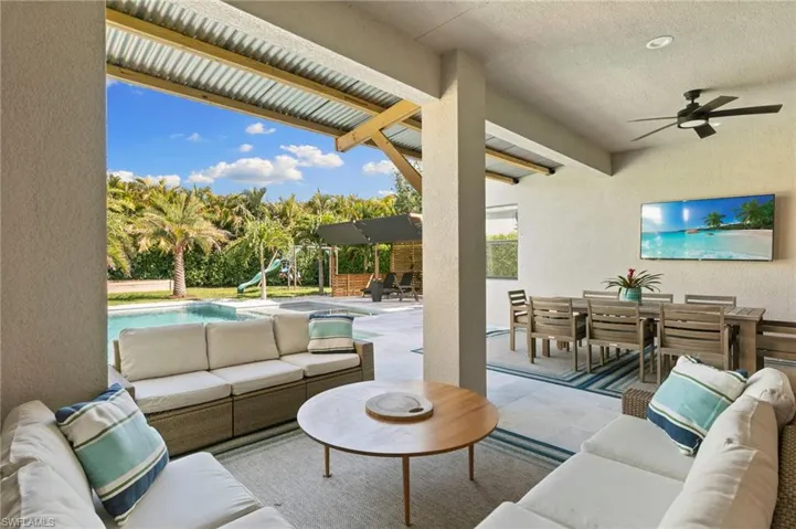 Living area featuring a textured wall, a ceiling fan, and beam ceiling