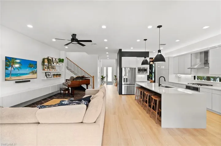 Living room featuring light wood-style flooring, a ceiling fan, stairway, and recessed lighting
