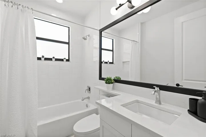 Bathroom featuring toilet, vanity, and shower / tub combo with curtain