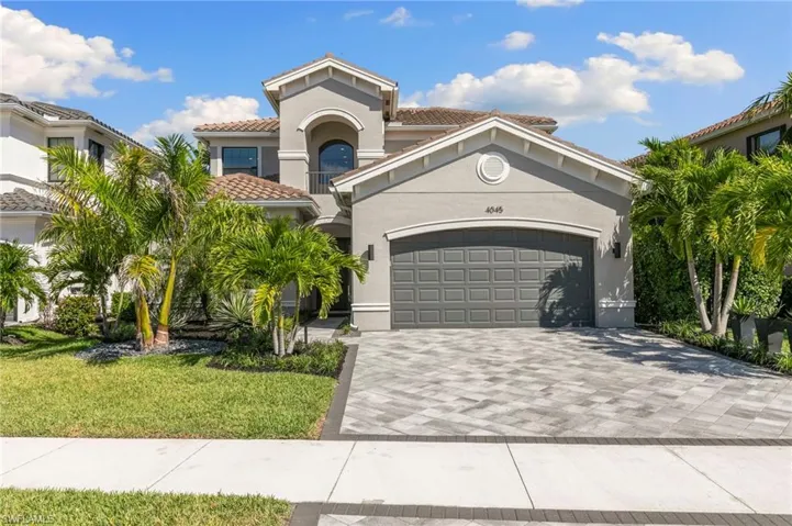Mediterranean / spanish-style house with stucco siding, decorative driveway, a front yard, a tile roof, and an attached garage
