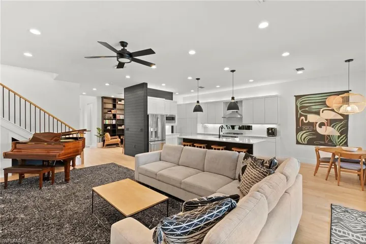 Living area featuring light wood-style flooring, ceiling fan, stairs, and recessed lighting
