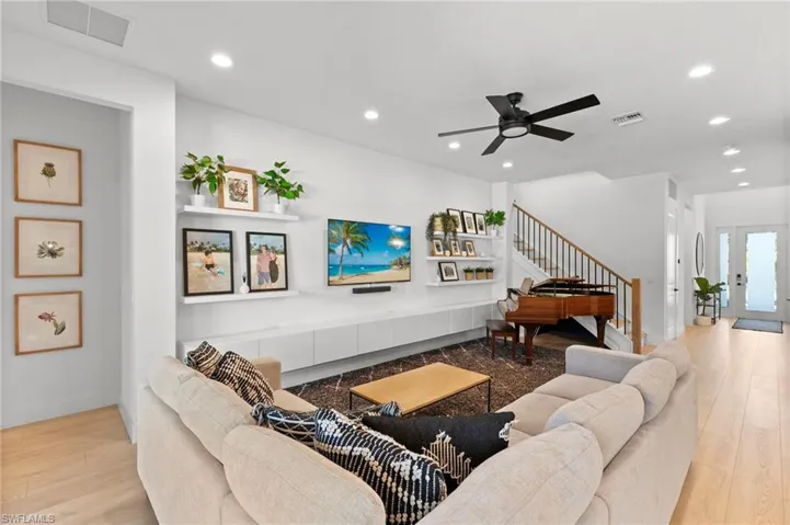 Living area featuring ceiling fan, visible vents, recessed lighting, wood finished floors, and stairs