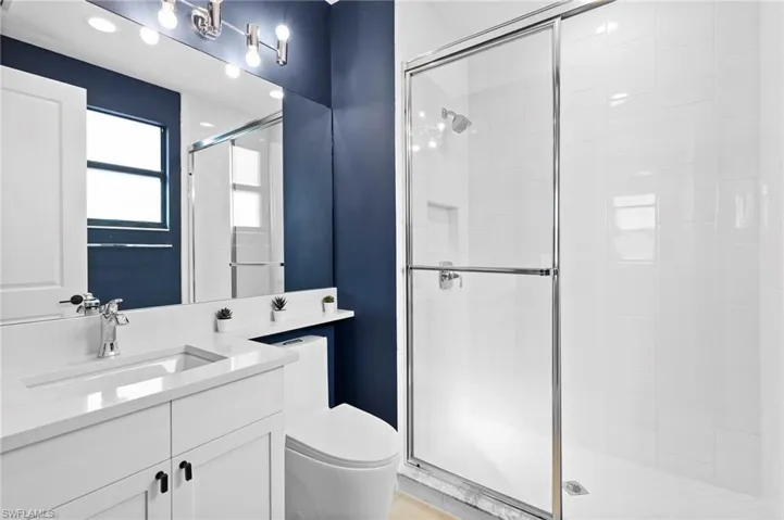 Bathroom with toilet, a stall shower, and vanity