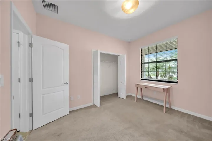 Neutral-toned carpet flooring, a built-in closet with bifold doors, and a window with horizontal blinds