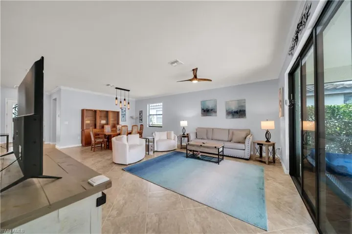 Open-concept living area featuring tile flooring, ceiling fan with integrated lighting, and a modern dining pendant light