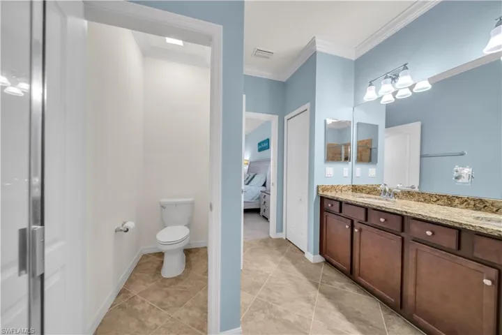 Bathroom featuring a tile floor, dual vanity with a stone countertop, and wood-finish cabinetry