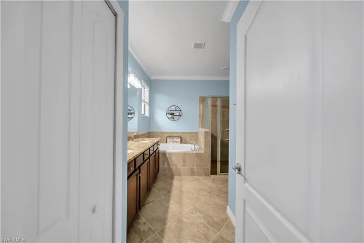 Dual vanity with undermount sinks, wood-finish cabinetry, and stone countertops