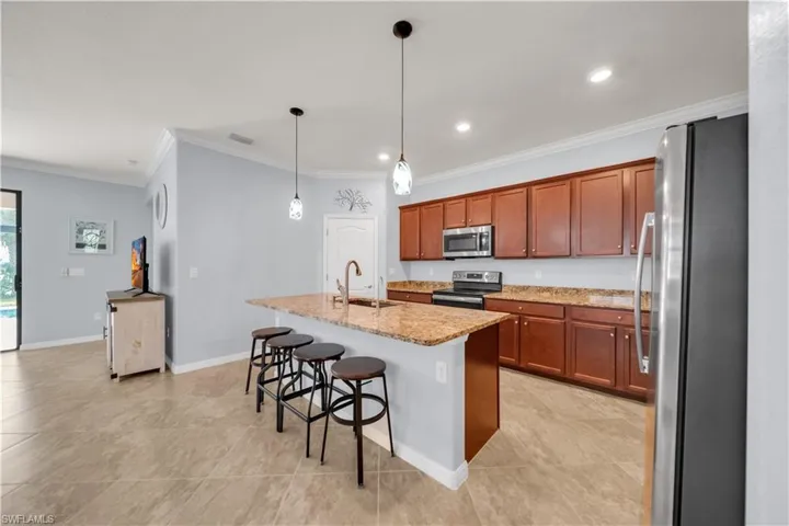 Kitchen featuring a center island, pendant lighting, built-in stainless steel appliances, wood cabinetry, and tiled flooring
