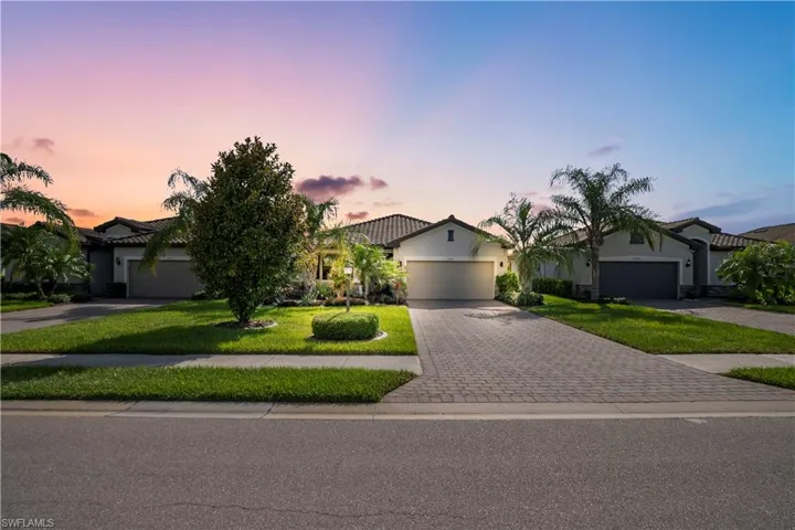 Single-story residence featuring a tile roof, paved driveway, and an attached garage
