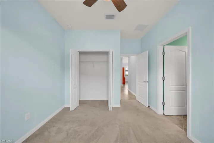 Soft blue walls, light carpet flooring, ceiling fan, and white paneled doors