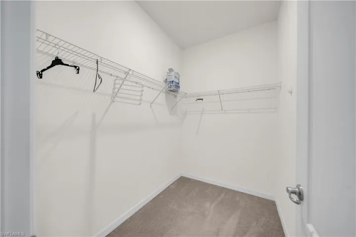 Light-colored carpeting with white baseboards, and white wire shelving