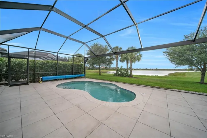 Screened enclosure featuring a freeform swimming pool, spacious patio, and water frontage
