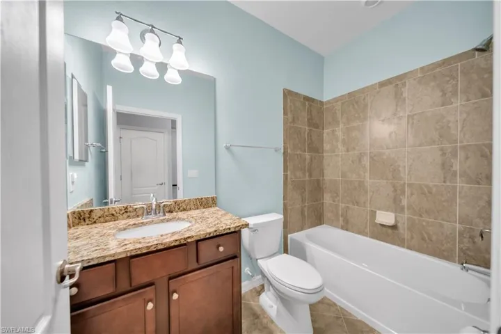 Bathroom featuring a single vanity with a stone countertop, an undermount sink, and a dark wood-finish cabinet