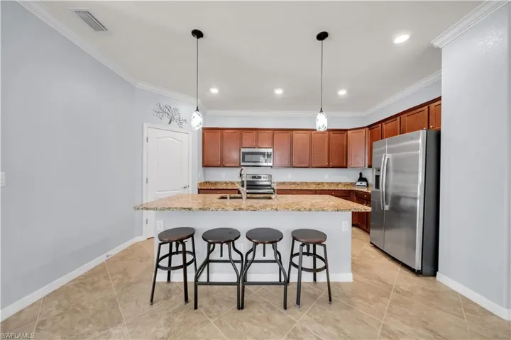 Kitchen featuring wood cabinetry, stainless steel appliances, a multi-level island with seating, and tile flooring