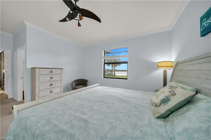 Window with water scenery, crown molding, ceiling fan, and carpeted flooring