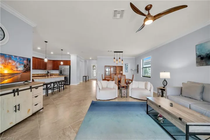 Spacious living area with tile flooring, crown molding, and recessed lighting