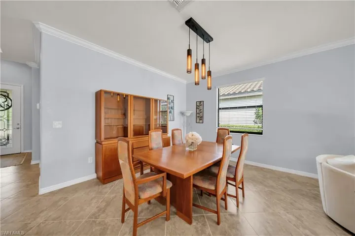 Recessed lighting, crown molding, tile flooring, modern linear chandelier, and a decorative glass front door