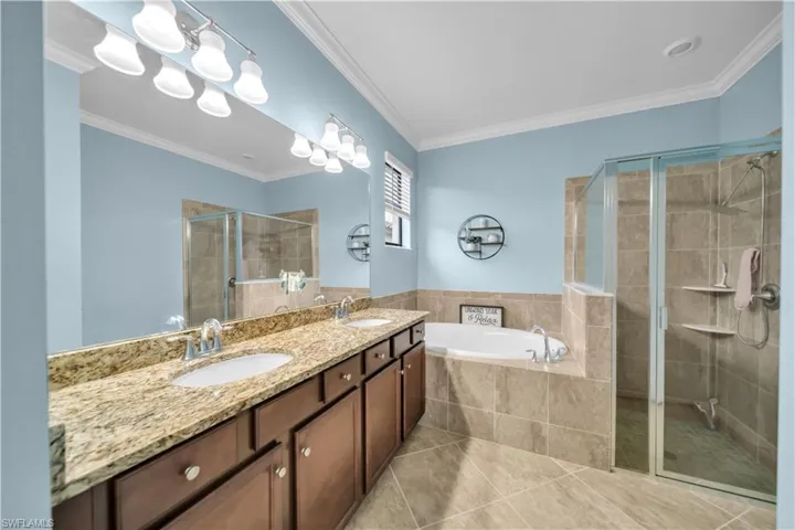 Dual vanity with stone countertop, built-in soaking tub, and glass-enclosed shower