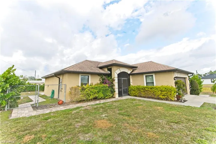 View of front of house with stucco siding, a gate, an attached garage, and a shingled roof