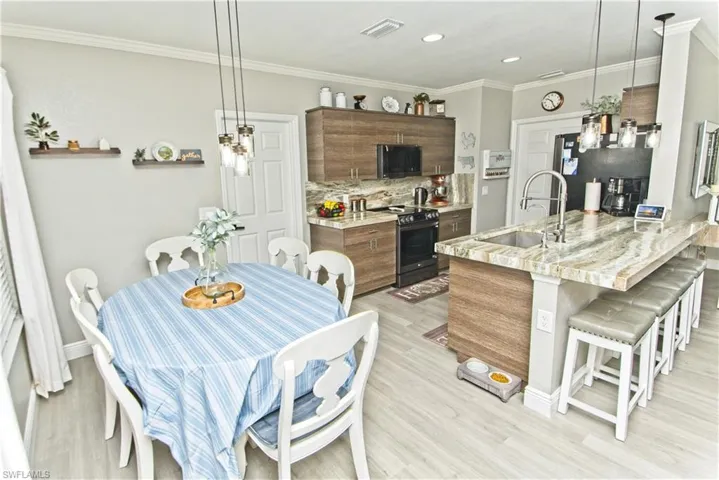 Kitchen with hanging light fixtures, modern cabinets, decorative backsplash, a kitchen breakfast bar, and stainless steel appliances