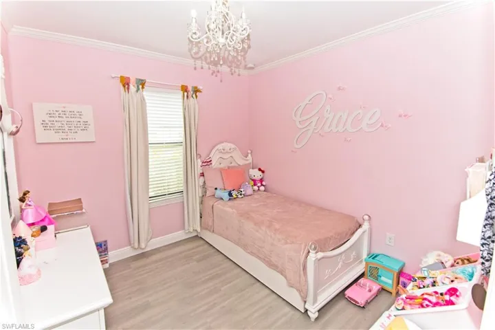 Bedroom with a chandelier, light wood finished floors, and crown molding