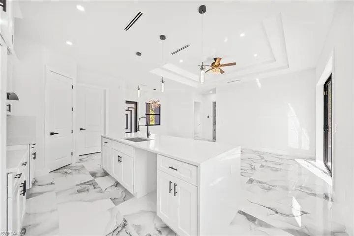 Bathroom with vanity, ceiling fan, recessed lighting, and a tray ceiling