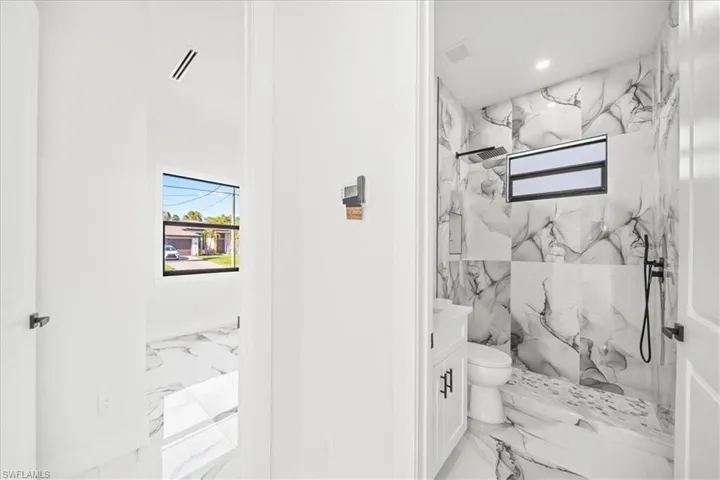 Bathroom with a marble finish shower, vanity, recessed lighting, and light marble finish flooring