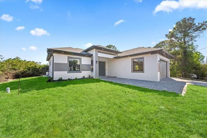 View of front of house featuring an attached garage, a front lawn, and stucco siding