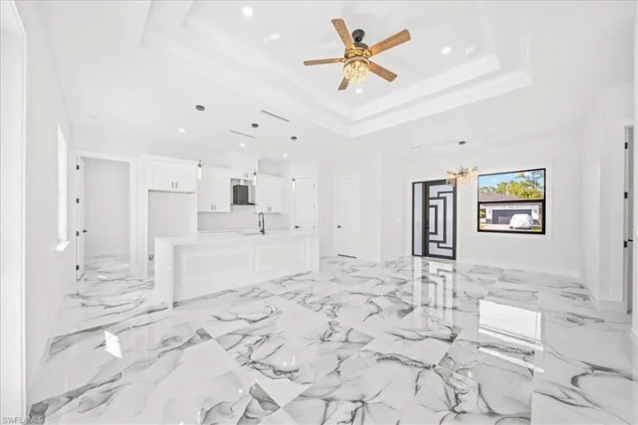 Unfurnished living room with ceiling fan, recessed lighting, and light marble finish flooring