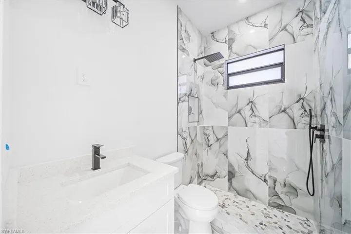 Bathroom featuring a marble finish shower and vanity