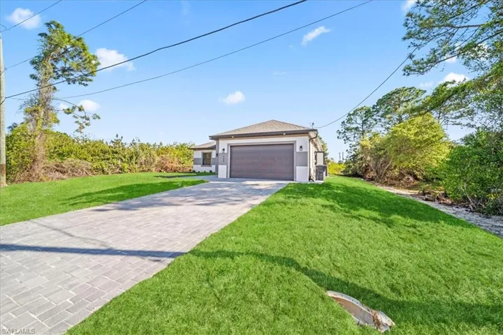 View of front of property featuring a front lawn, driveway, and an attached garage