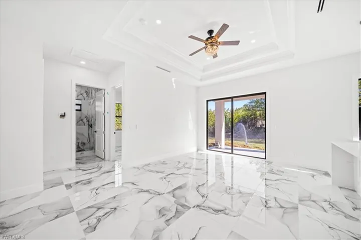 Unfurnished room with ceiling fan, healthy amount of natural light, recessed lighting, and light marble finish flooring