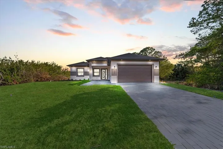 Prairie-style home featuring an attached garage, stucco siding, driveway, and a front lawn