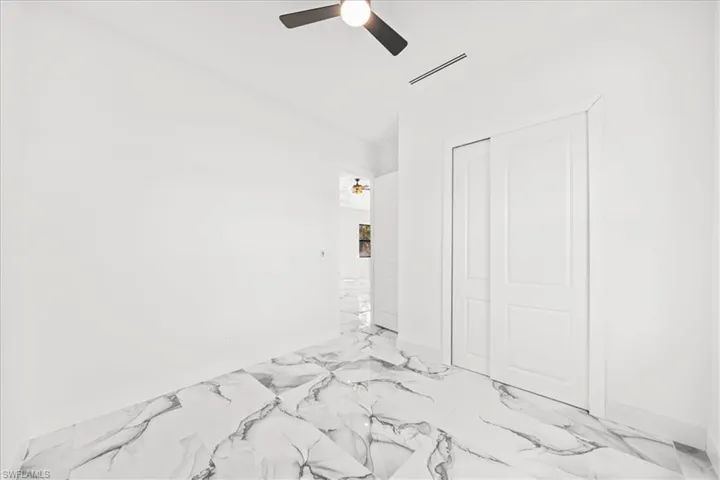 Unfurnished bedroom with ceiling fan, a closet, and light marble finish floors